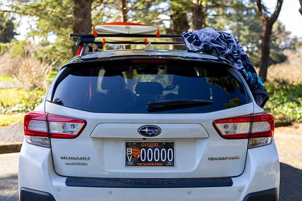 Subaru with surf boards and towels on roof